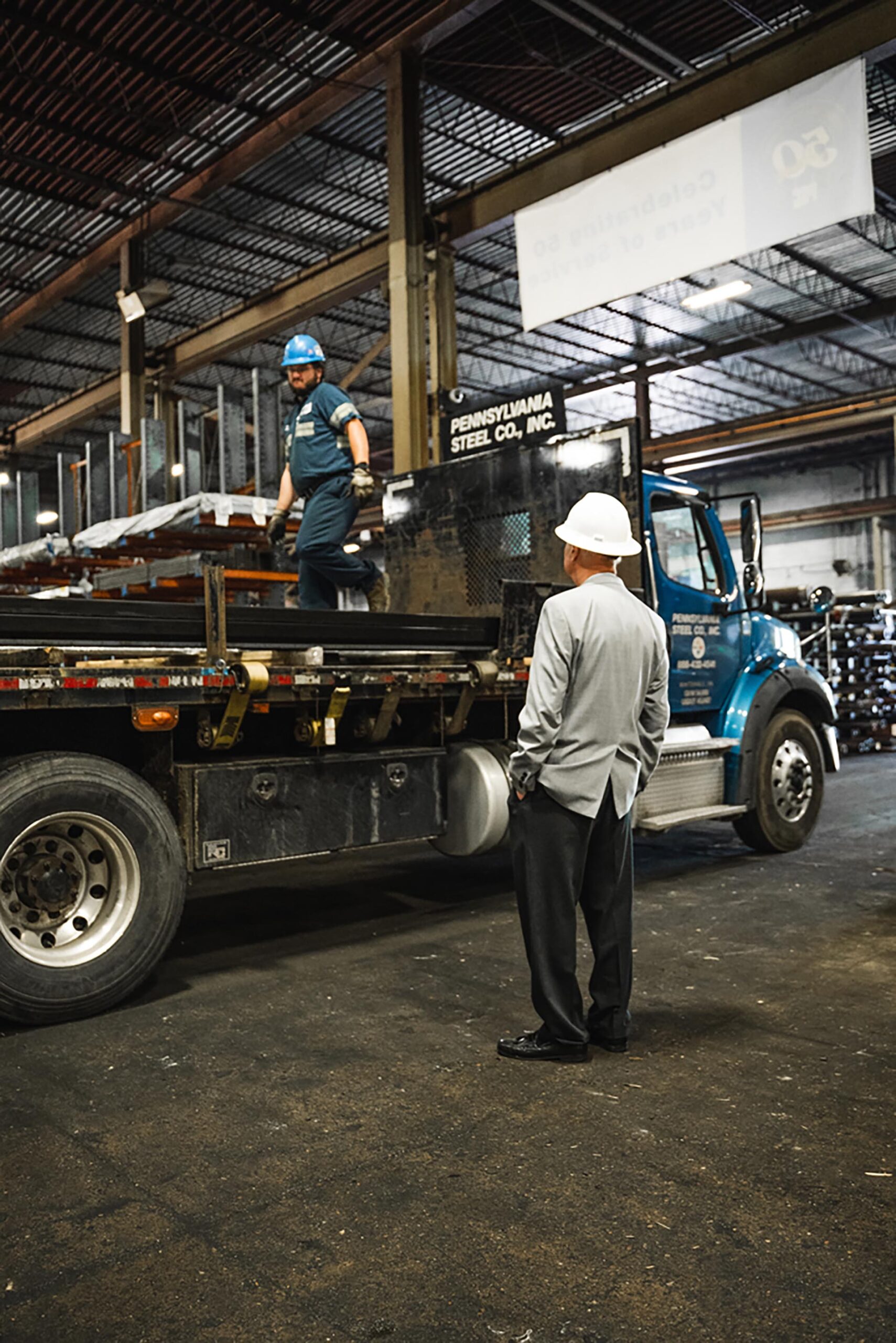 Two PA Steel employees talking while loading metal onto a delivery truck