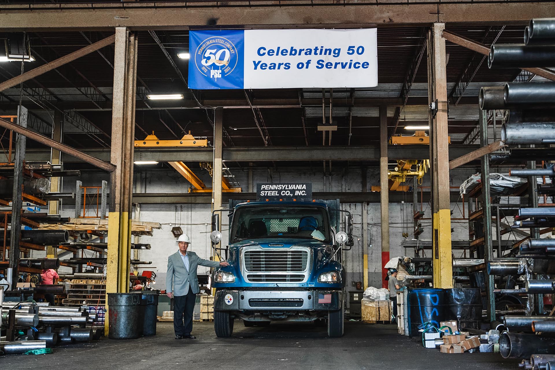 PA Steel truck in warehouse with banner reading "Celebrating 50 years of service" hanging above it
